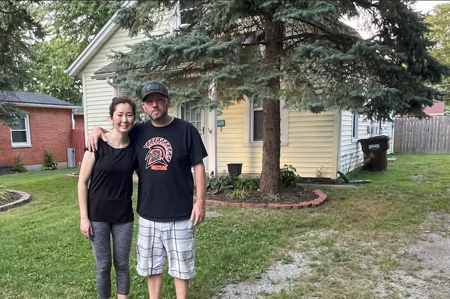 Josh and his wife in front of their very first flip property