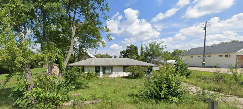 Rental property before EZ Rent Now rehab &mdash; overgrown yard and dated exterior