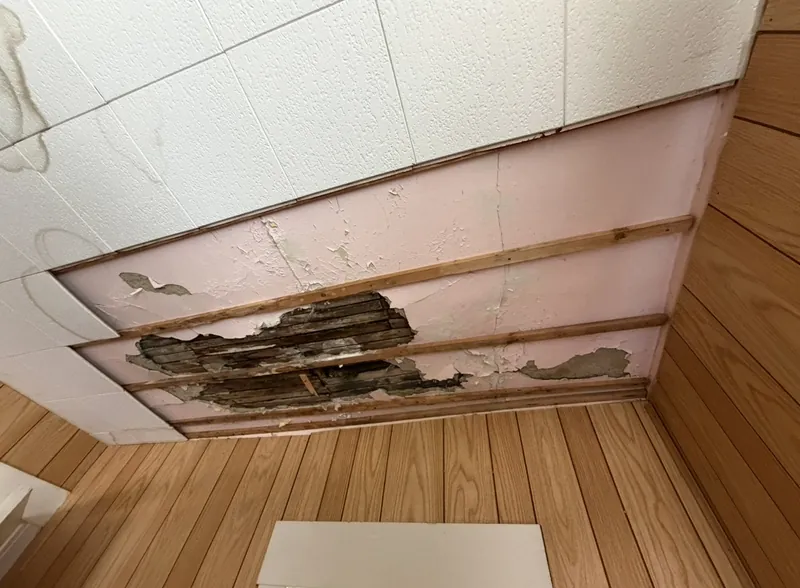 Water-damaged ceiling before EZ Rent Now repair &mdash; hole exposing furring strips and damaged backing