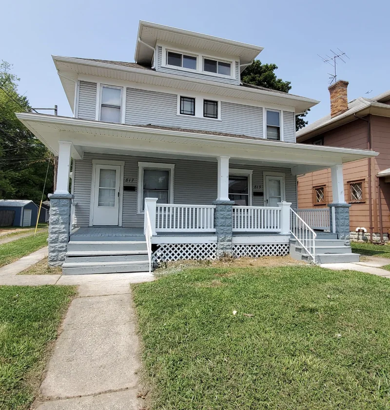 Same Springfield, OH rental duplex after EZ Rent Now rehab &mdash; mowed lawn, freshly painted porch, ready for tenants